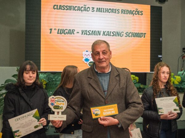 Presidente da cooperativa entregando prêmio a estudante vencedora do Palavras de Ouro